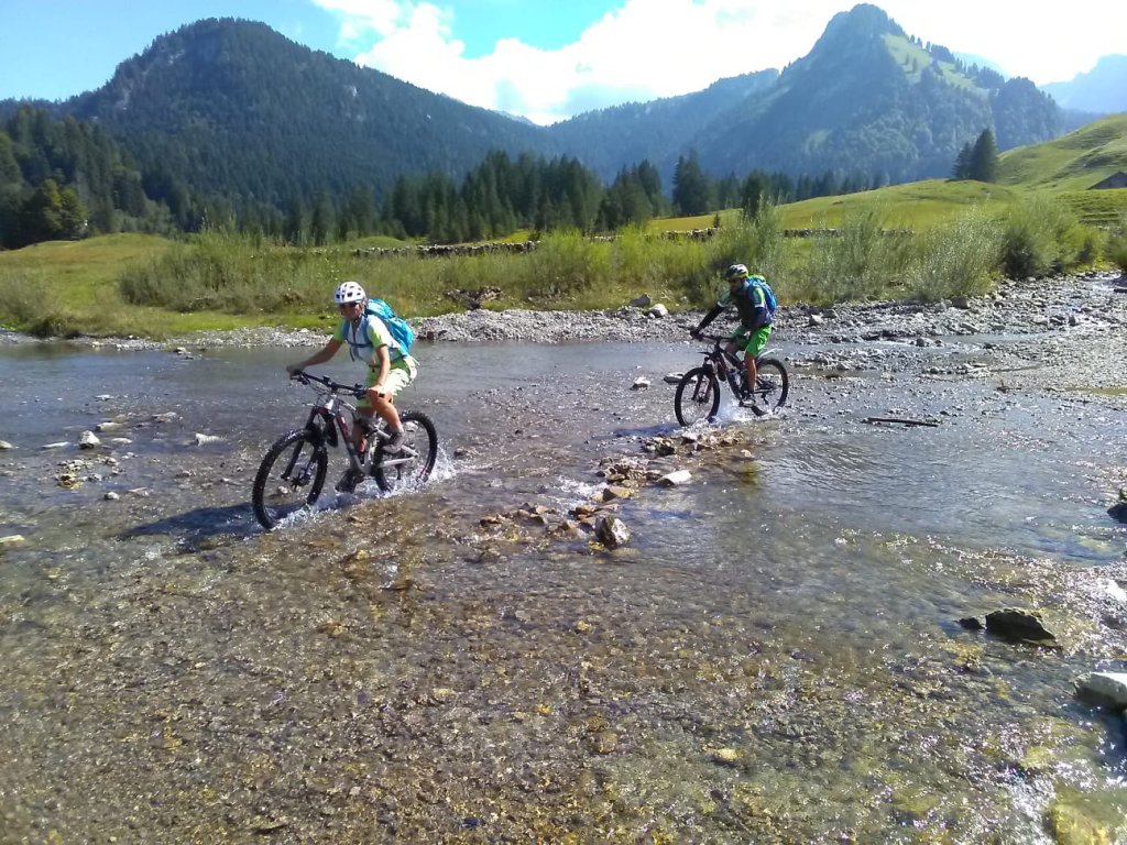zwei Mountainbiker durch eine Furt im Fluss fahrend