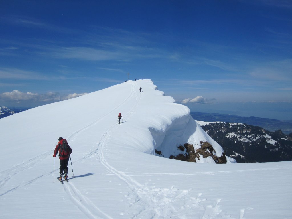 Skitourengeher gehen bergauf über eine große weisse Schneefläche